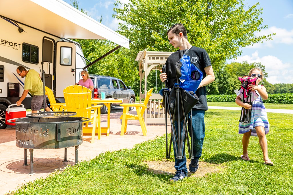 Family unpacking the RV at a KOA campground.