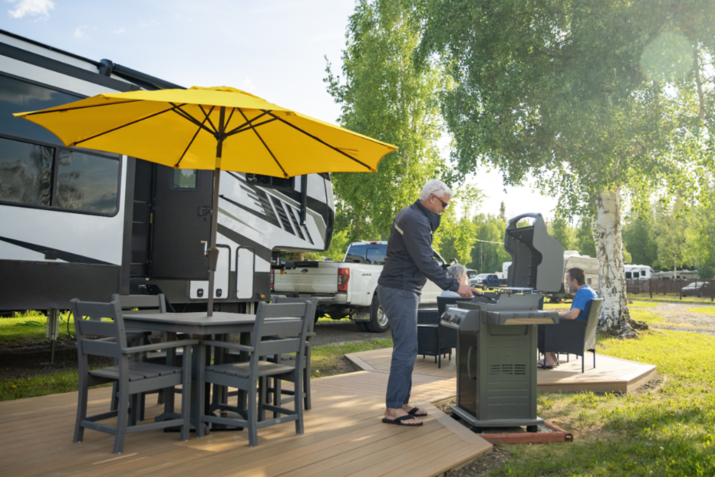 Man grilling at pull thru RV site at Fairbanks Chena River KOA Holiday